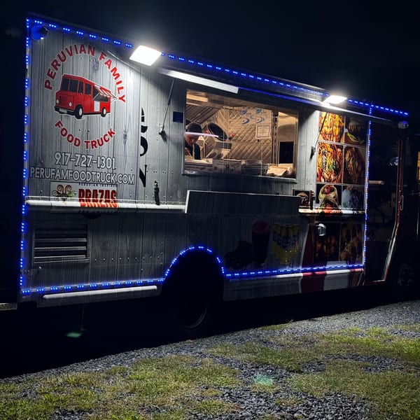 Brazas BBQ Chicken food truck, illuminated with blue lights, at night.