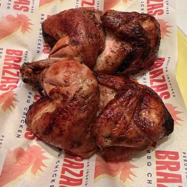 Four pieces of Peruvian BBQ chicken with crispy skin, served on Brazas branded parchment paper.